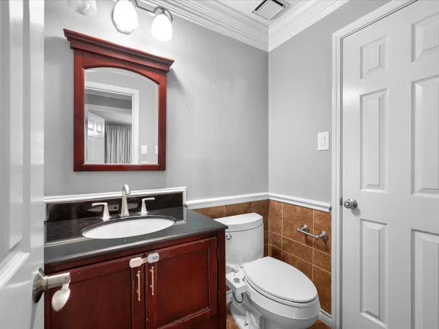 a bathroom with a toilet sink vanity and mirror