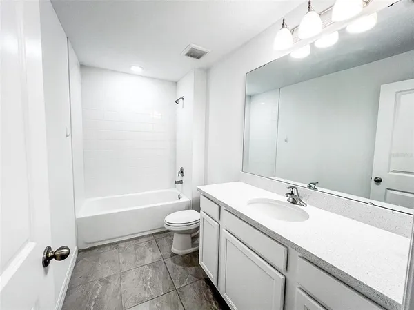 a bathroom with a sink a toilet a mirror and bathtub