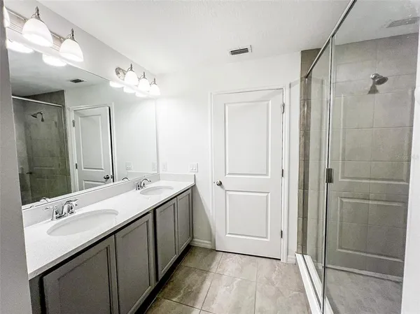 a bathroom with a double vanity sink mirror and shower