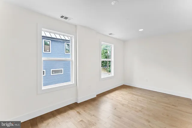 an empty room with wooden floor and windows