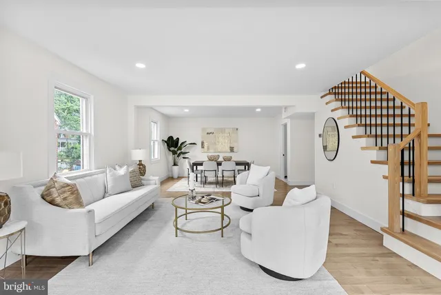 a living room with furniture white walls and a large window