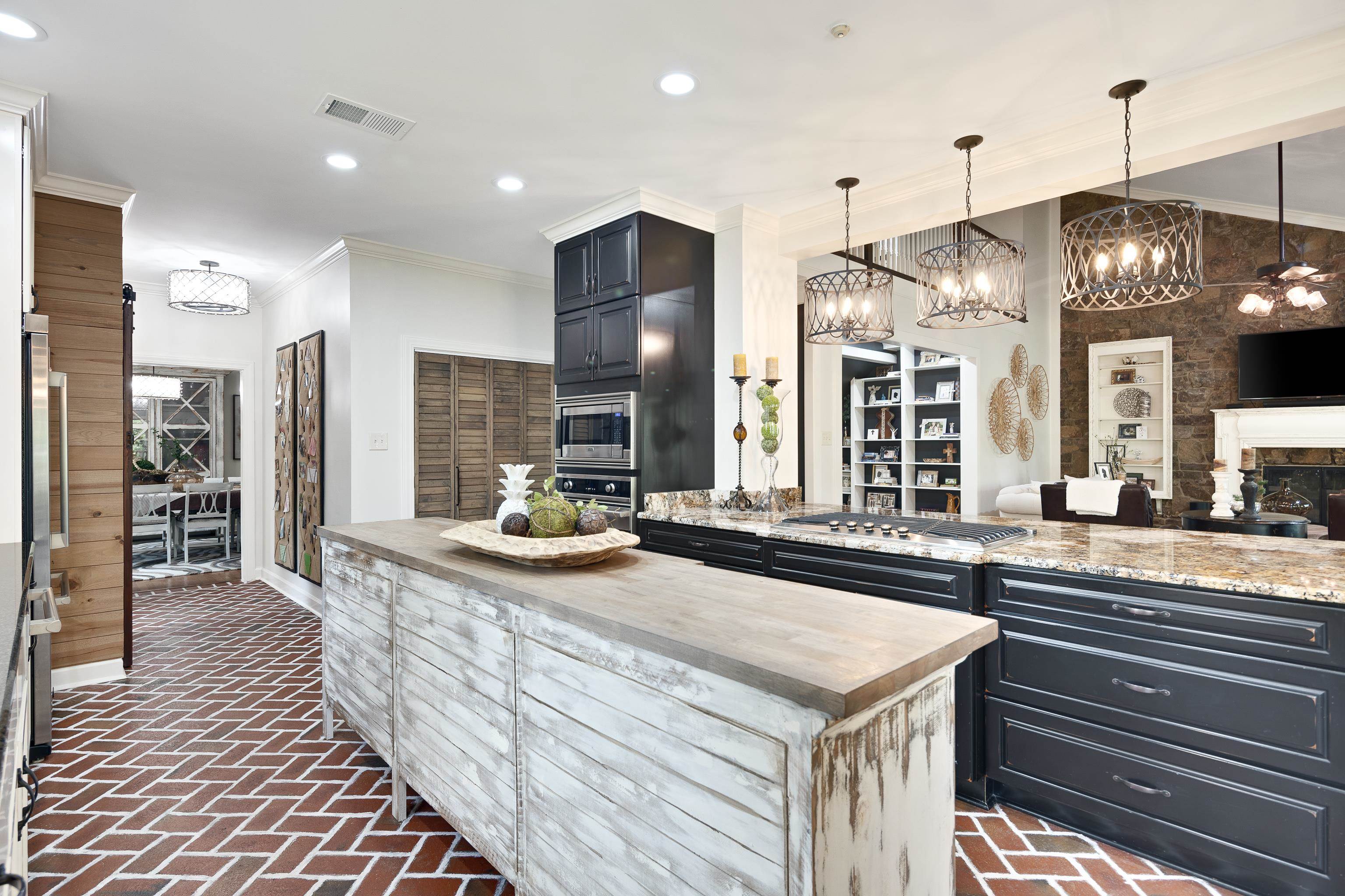 811 Sweetbrier Road Memphis, TN 38120 - Photo 13 of 40 Kitchen featuring herringbone brick flooring, two-tiered island with wood-finish countertop, dark cabinetry, built-in stainless steel appliances, and granite countertops