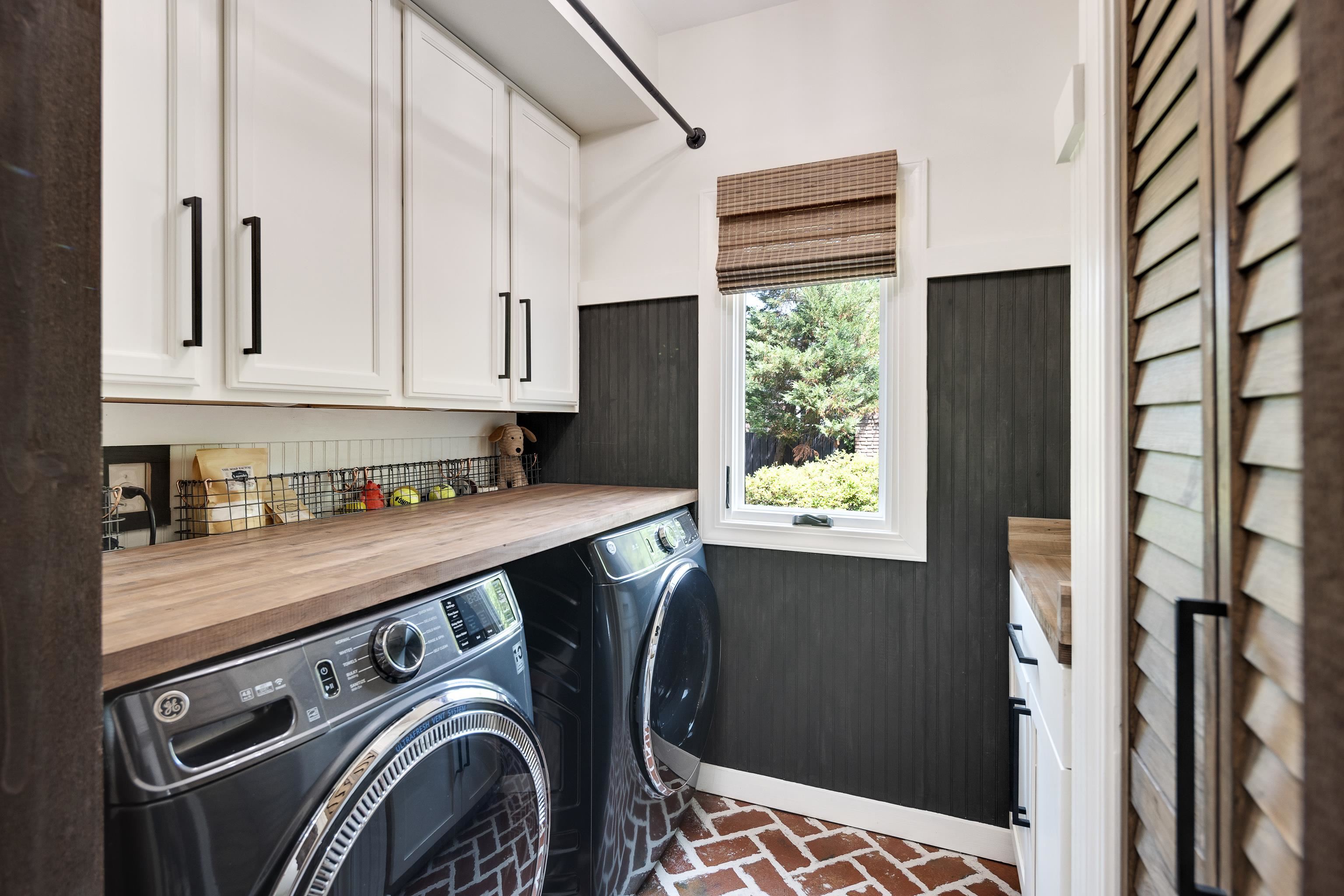 811 Sweetbrier Road Memphis, TN 38120 - Photo 16 of 40 Laundry room featuring white shaker-style cabinetry with matte black hardware, wood-finish countertops, and a brick-patterned floor