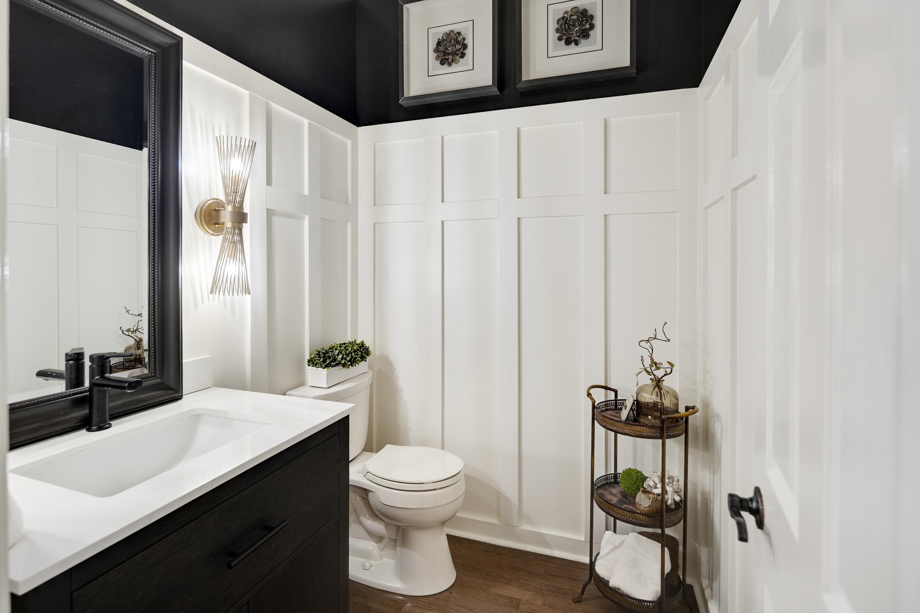 811 Sweetbrier Road Memphis, TN 38120 - Photo 19 of 40 Powder room featuring board and batten wainscoting, a dark vanity with a white countertop, and wood-finish flooring