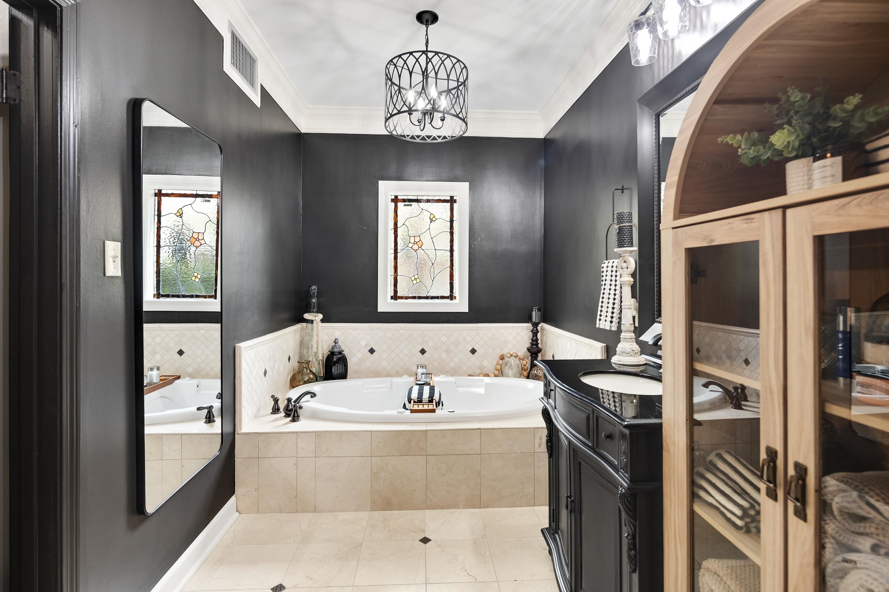 811 Sweetbrier Road Memphis, TN 38120 - Photo 22 of 40 Soaking tub with bronze fixtures set against a tiled surround and black walls