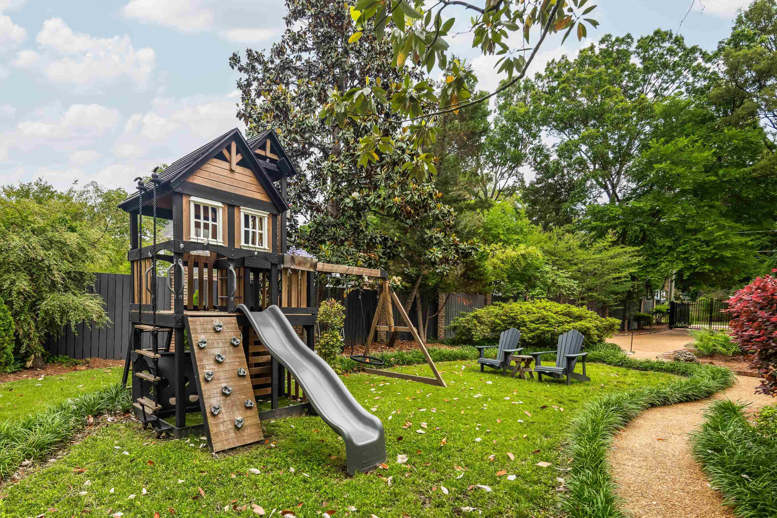 811 Sweetbrier Road Memphis, TN 38120 - Photo 33 of 40 Expansive backyard featuring a custom wooden play structure with a slide and rock climbing wall, mature trees, a gravel pathway, and dedicated seating area
