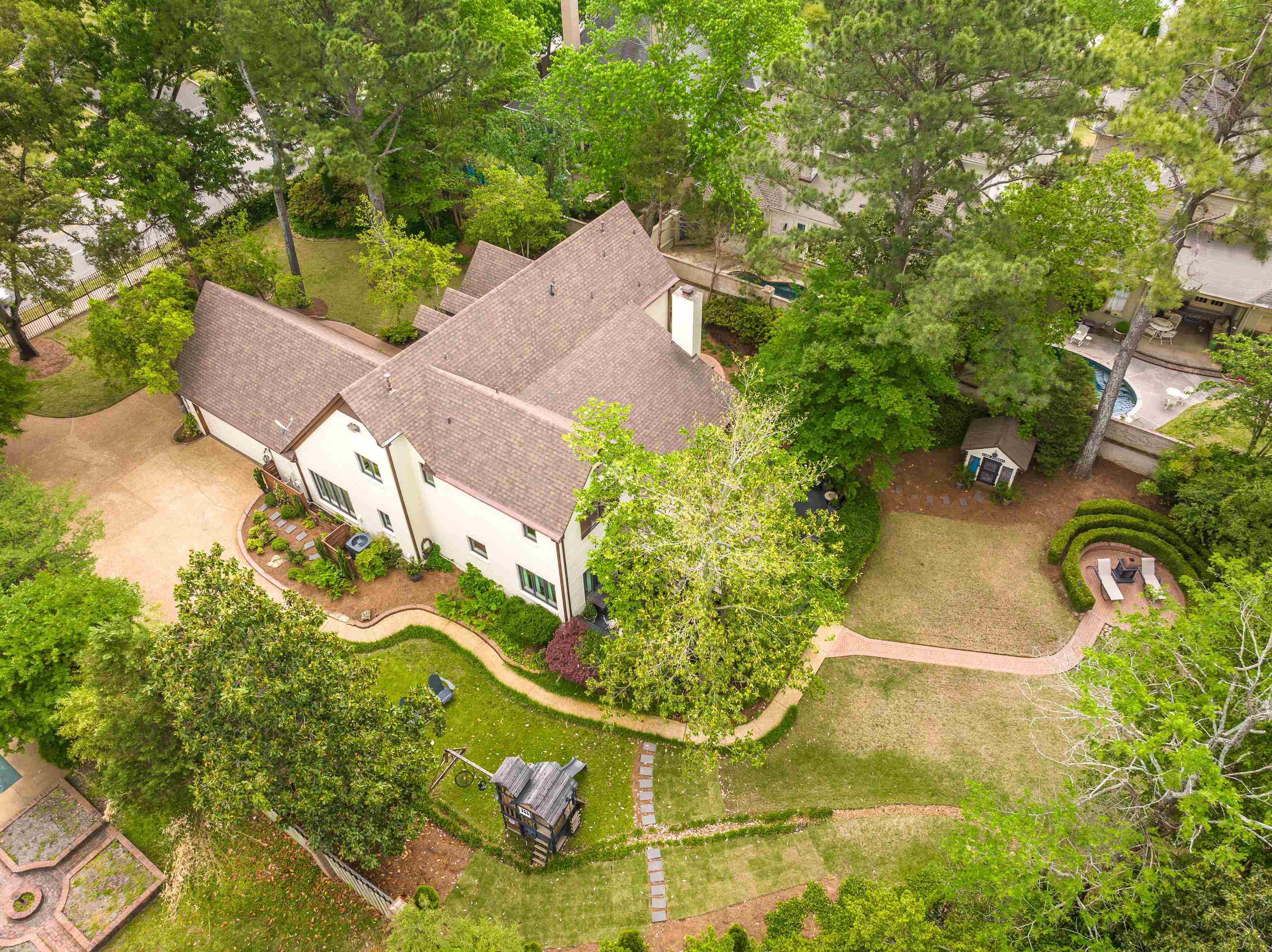 811 Sweetbrier Road Memphis, TN 38120 - Photo 39 of 40 Expansive rear yard featuring a brick pathway, mature trees, manicured lawn, and a circular hardscaped patio area