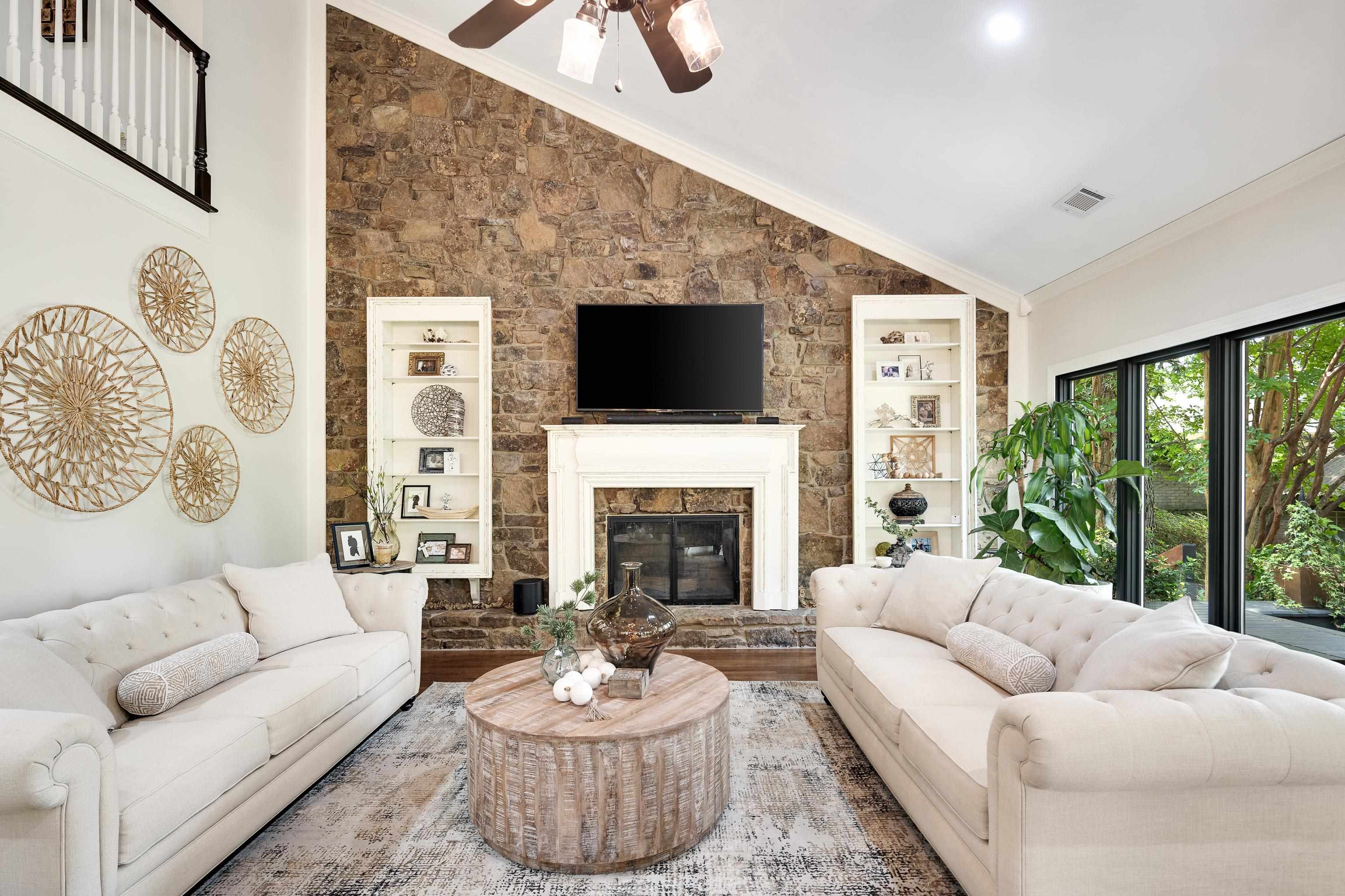 811 Sweetbrier Road Memphis, TN 38120 - Photo 7 of 40 Vaulted ceiling living area featuring a prominent stone fireplace, built-in shelving, large black-framed windows, and an upper-level railing