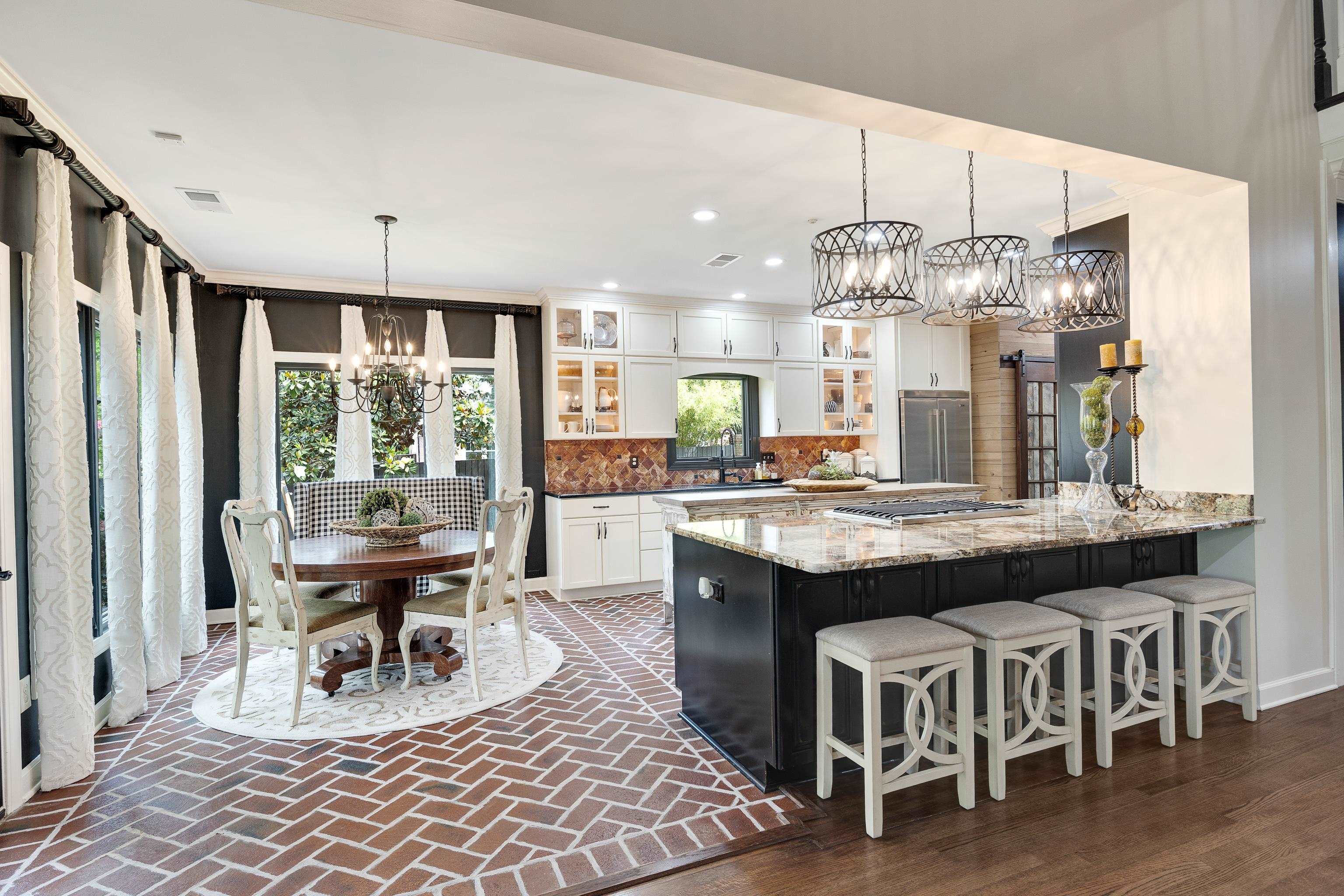 811 Sweetbrier Road Memphis, TN 38120 - Photo 10 of 40 Open-concept kitchen and dining area featuring a large center island with seating, pendant lighting, white cabinetry, and herringbone-pattern brick-finish flooring in the dining space