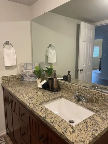 a bathroom with a granite countertop sink and a mirror