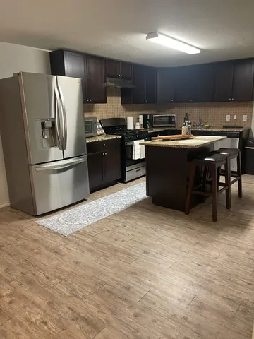 a kitchen with stainless steel appliances granite countertop a refrigerator a stove a sink and a microwave