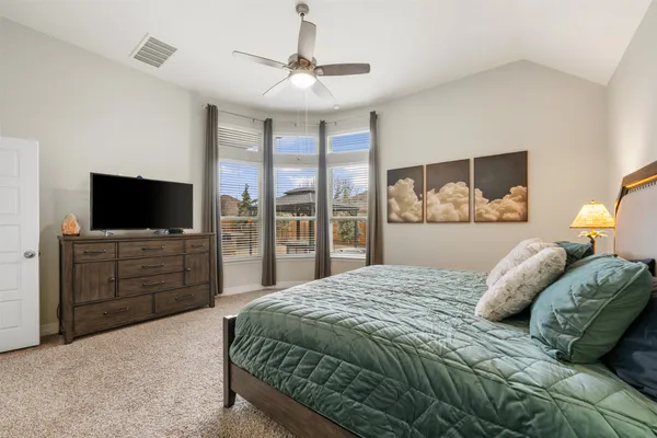 a spacious bedroom with a bed and a flat tv screen