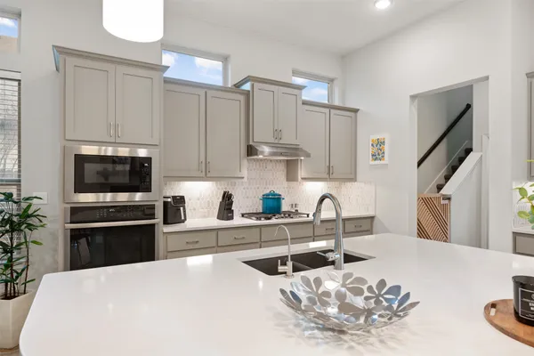 a kitchen with stainless steel appliances kitchen island granite countertop a sink dishwasher a refrigerator and a stove with wooden floor