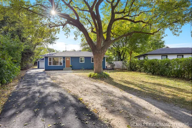 a front view of a house with a yard and large trees