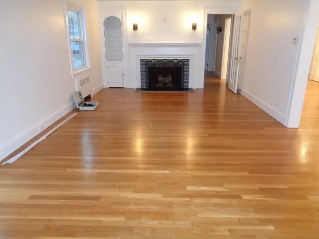 a view of a livingroom with wooden floor and a fireplace