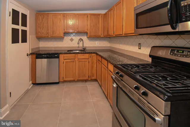 a kitchen with granite countertop a sink stove and cabinets