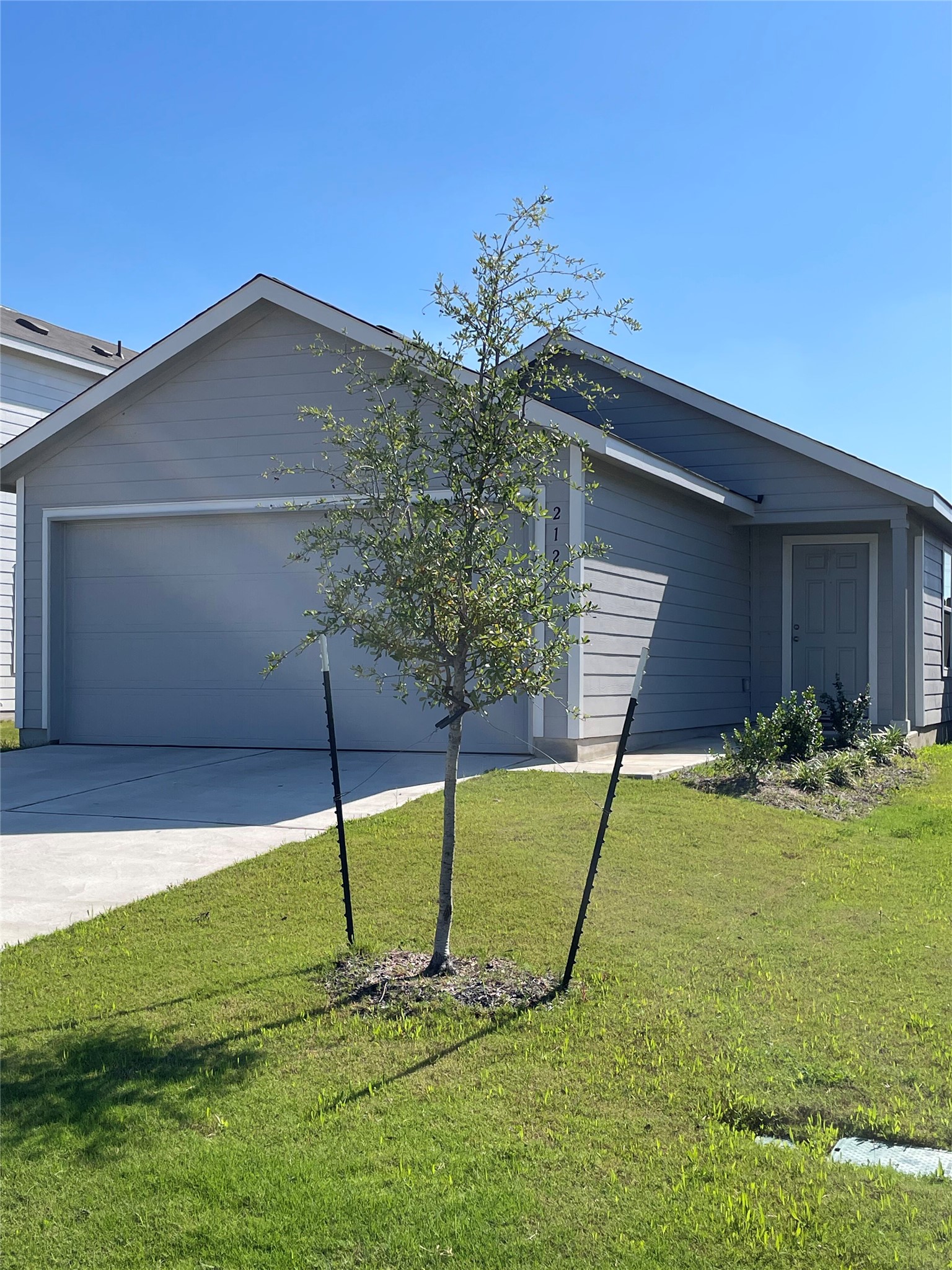 Single-story residence featuring light gray horizontal siding, an attached two-car garage, and a covered entry