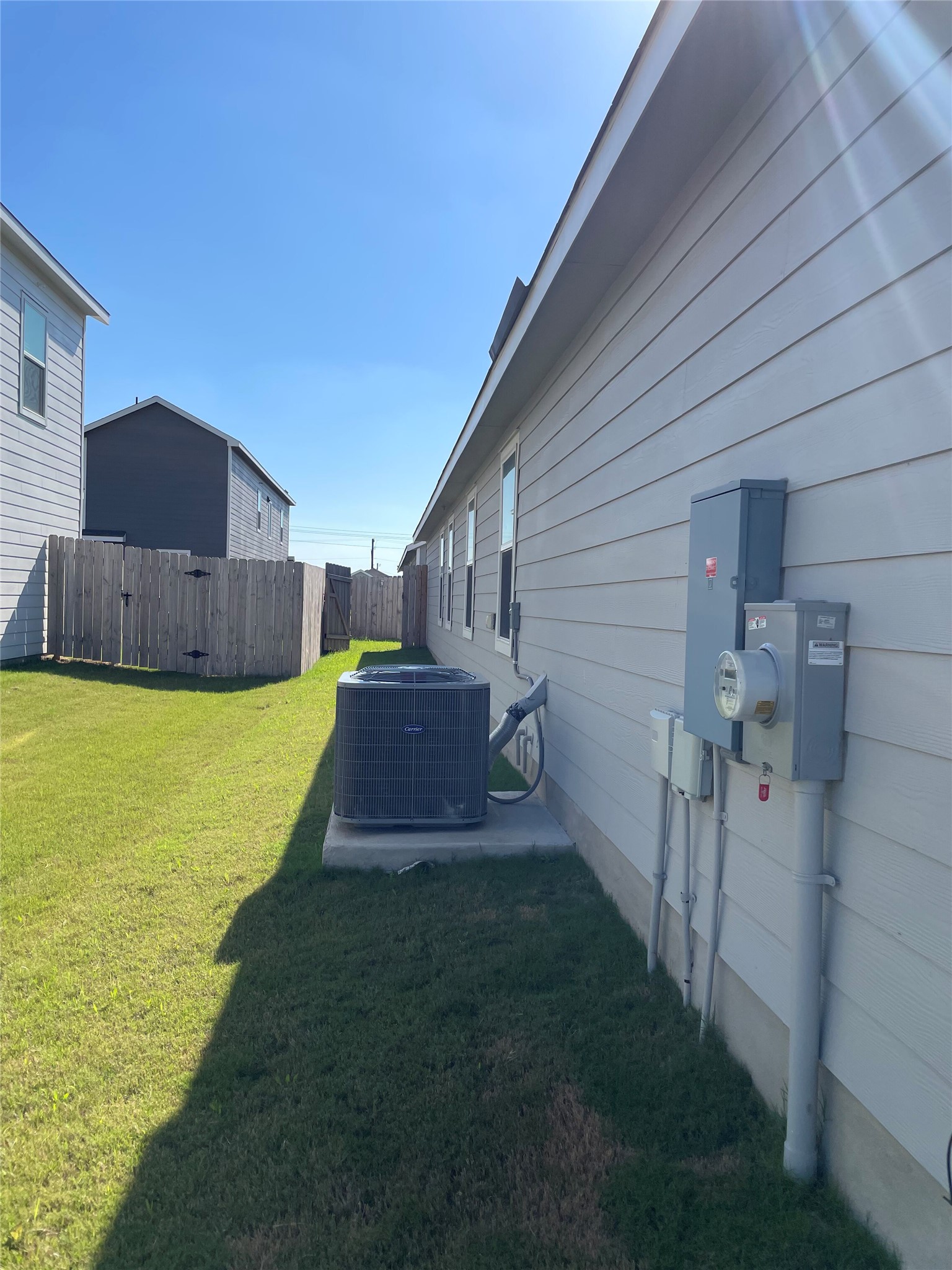 212 Marty Allen Loop Jarrell, TX 76537 - Photo 13 of 13 Exterior siding with multiple windows, an HVAC unit on a concrete pad, and utility meters