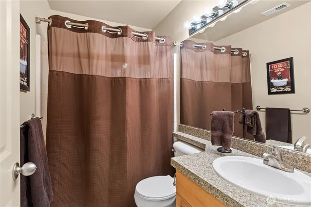 a bathroom with a sink a toilet a mirror and shower curtain