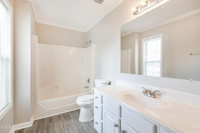 a bathroom with a bathtub shower sink mirror and toilet