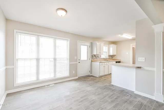 a kitchen with white cabinets and wooden floor