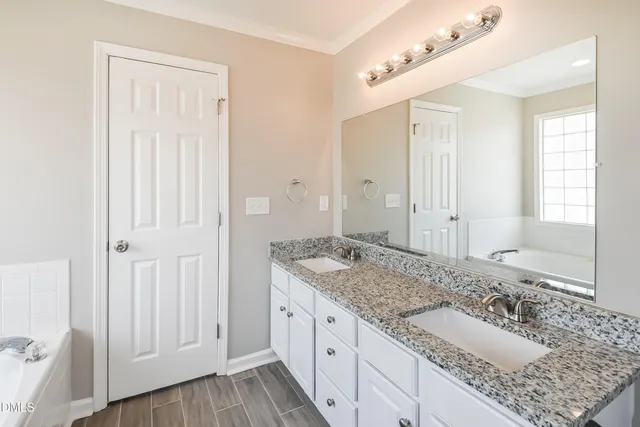 a bathroom with a granite countertop double vanity sink and mirror