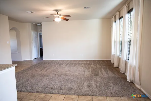 a view of a big room with chandelier fan and windows
