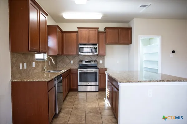 a kitchen with stainless steel appliances granite countertop a sink stove and refrigerator
