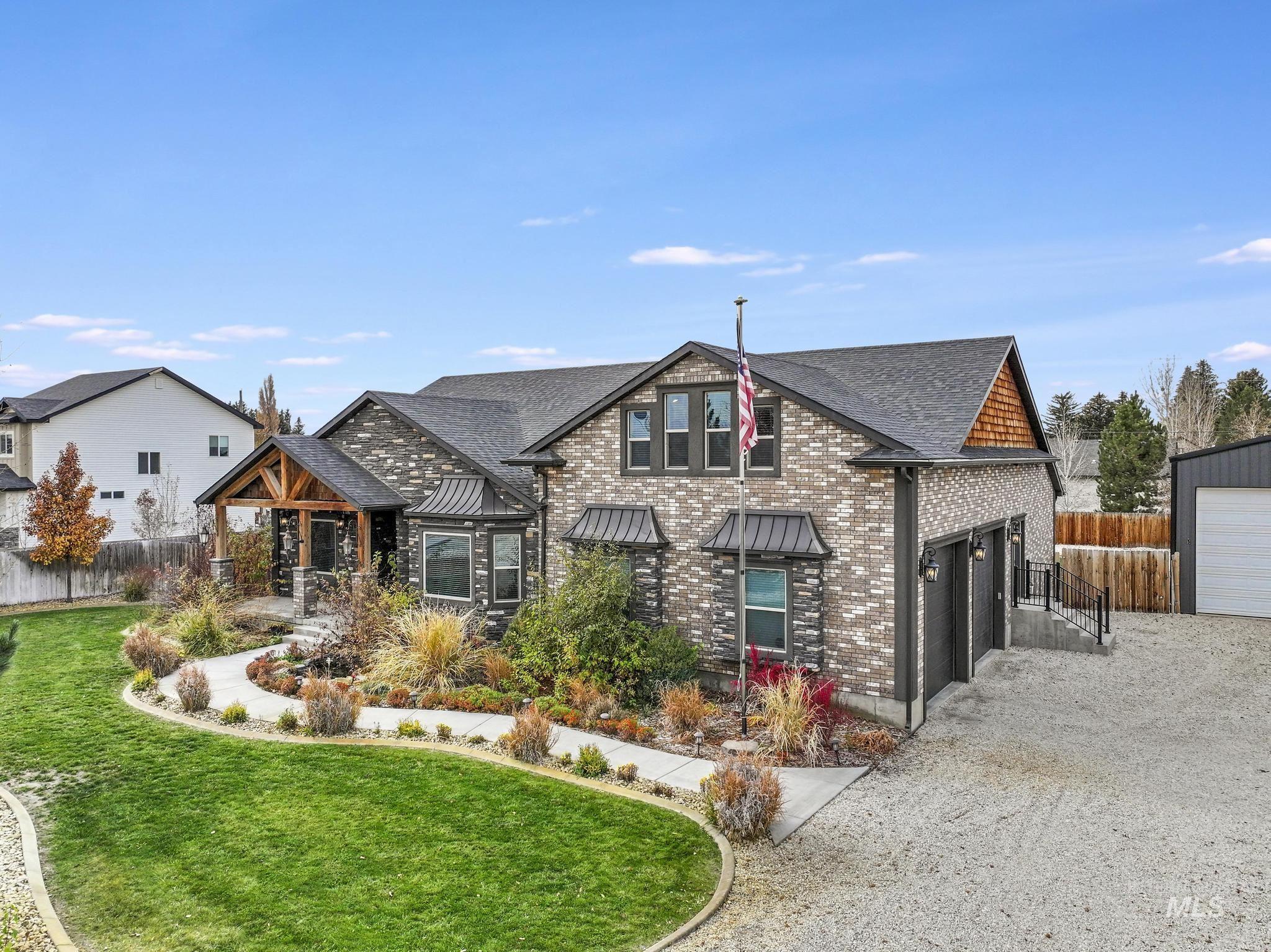 View of front facade featuring a garage, gravel driveway, and a shingled roof