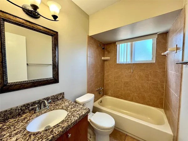 a bathroom with a granite countertop sink toilet mirror and bathtub