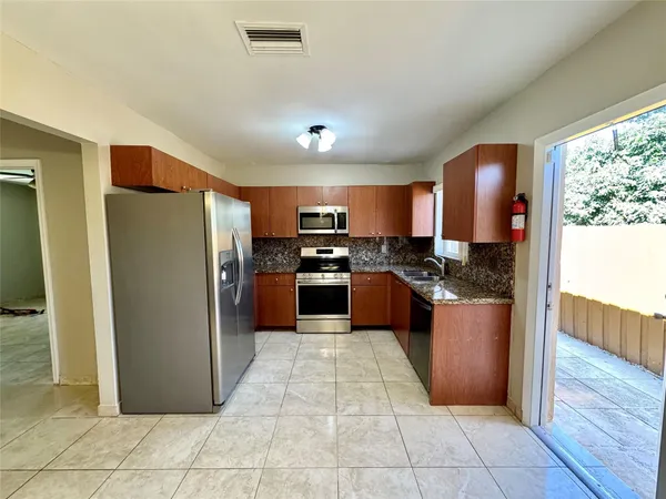 a large kitchen with stainless steel appliances granite countertop a refrigerator and a sink