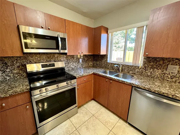 a kitchen with granite countertop a stove a sink and a microwave