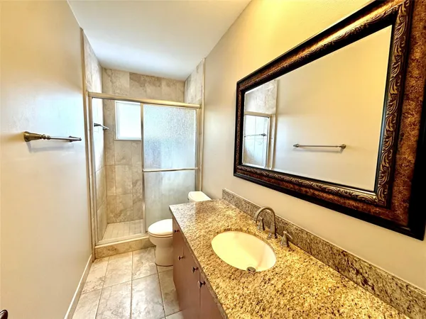 a bathroom with a granite countertop sink mirror vanity and a shower