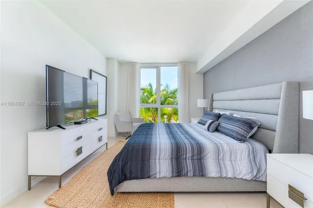 a bedroom with a bed a dresser and a large window