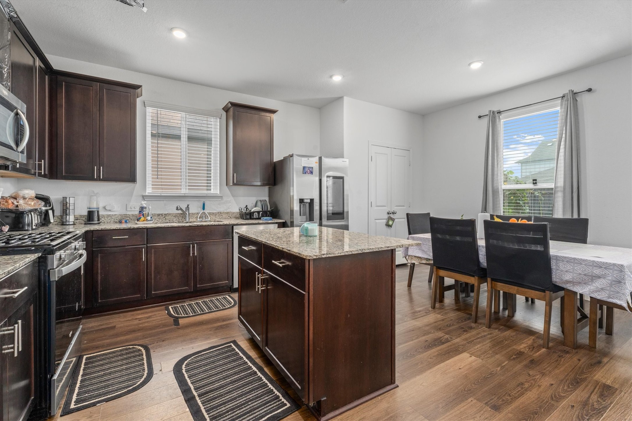 5826 Finely Run St Spring Spring, TX 77373 - Photo 15 of 38 a kitchen with stainless steel appliances granite countertop a stove top oven a sink dishwasher a dining table and chairs with wooden floor