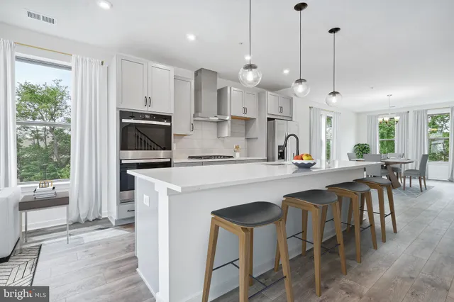 a kitchen with stainless steel appliances kitchen island a large island in the center and wooden floors