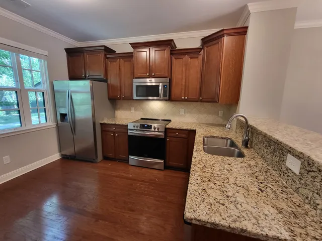 a kitchen with stainless steel appliances granite countertop a refrigerator sink and stove