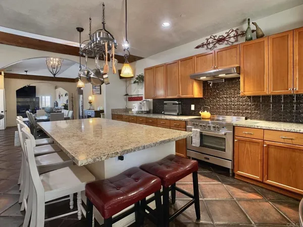a kitchen with stainless steel appliances kitchen island granite countertop a table chairs in it and wooden floors