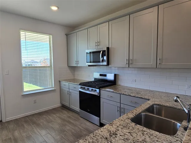 a kitchen with granite countertop a sink and a stove top oven