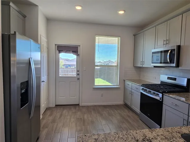 a kitchen with granite countertop a refrigerator stove and microwave