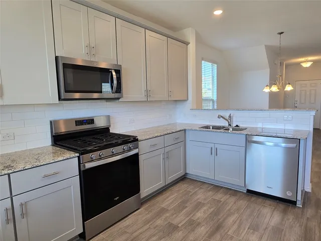 a kitchen with granite countertop white cabinets and stainless steel appliances
