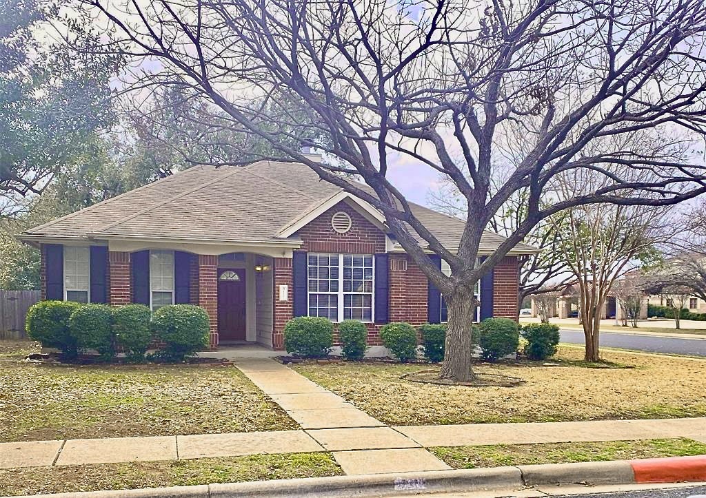 Single story home featuring a shingled roof, a front yard, and brick siding