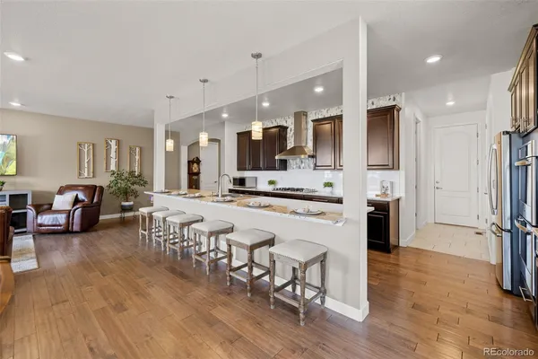 a large white kitchen with lots of counter space dining table and stainless steel appliances