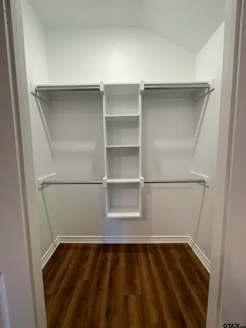 a walk in closet with wooden floor