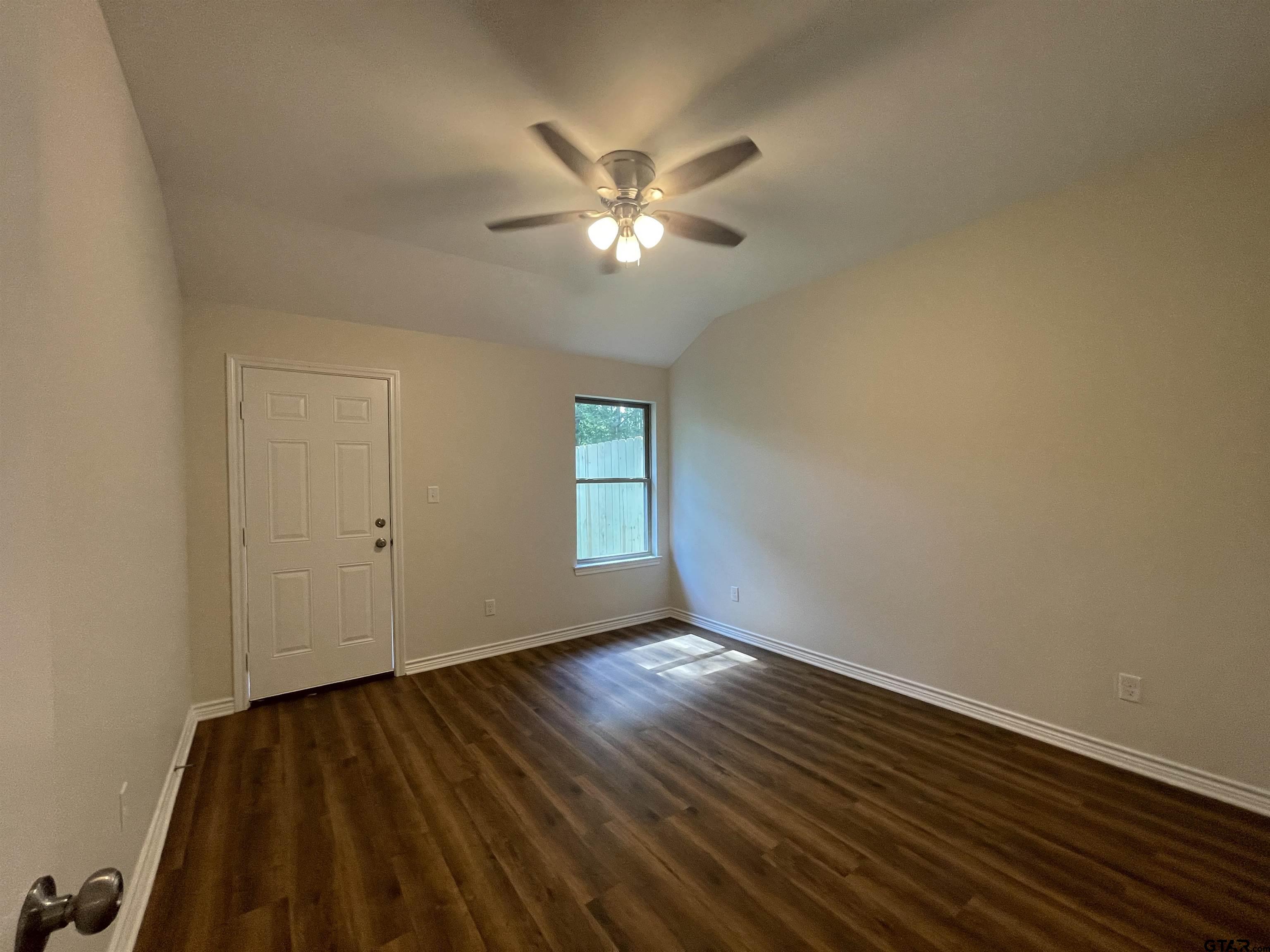 4074 W Creek, Unit 18 Tyler, TX 75703 - Photo 9 of 11 a view of an empty room with wooden floor and a ceiling fan