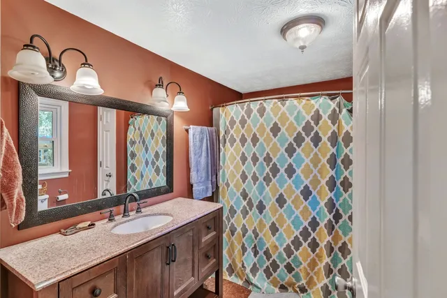 a bathroom with a granite countertop sink a mirror and a shower