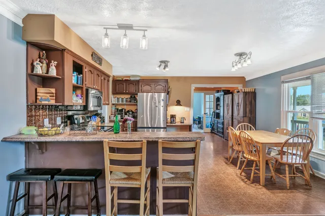 a dining hall with stainless steel appliances granite countertop a dining table and chairs