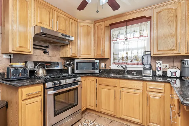 a kitchen with stainless steel appliances granite countertop a stove a sink and a microwave