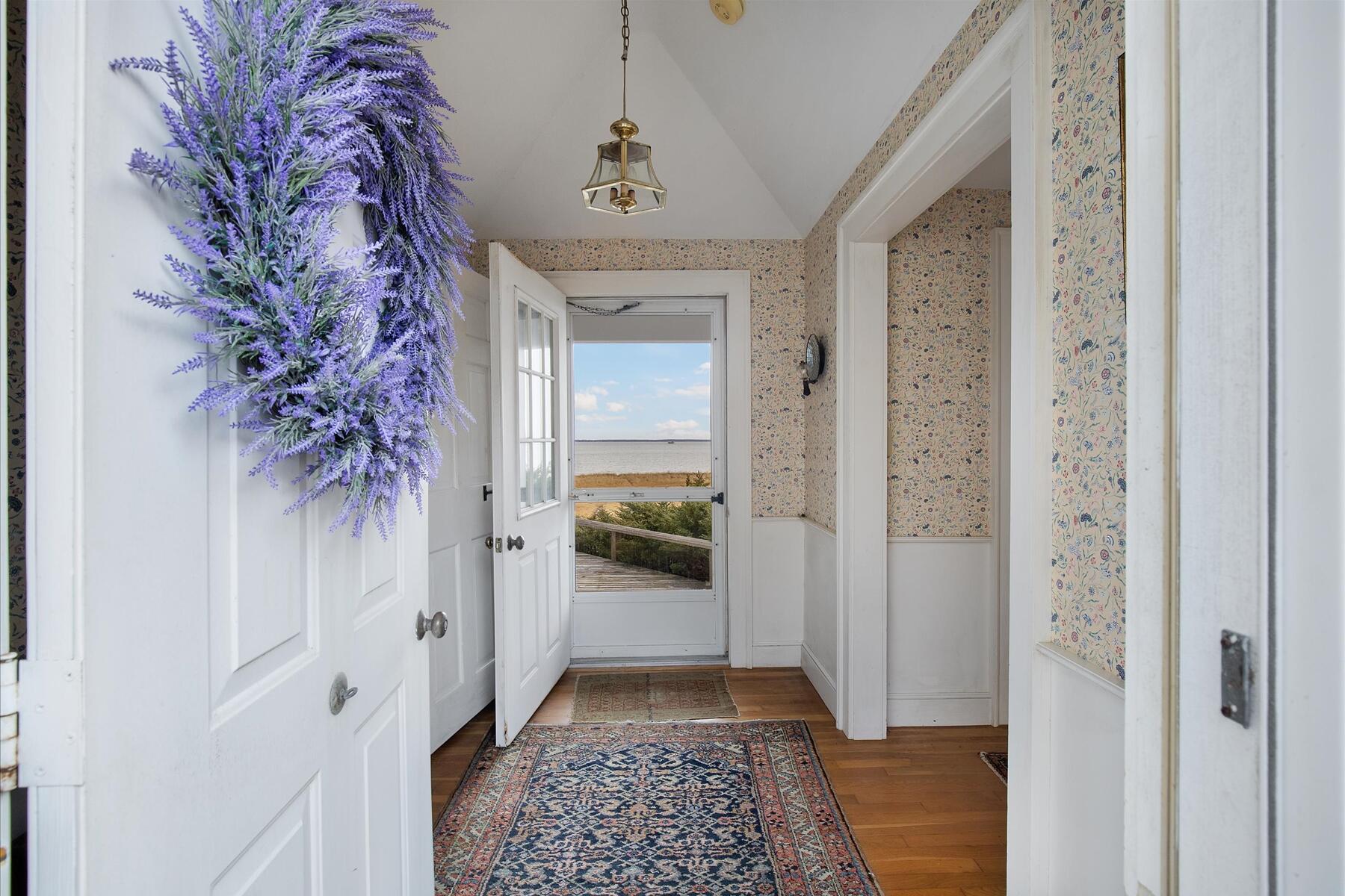 495 Chequessett Neck Road Wellfleet, MA 02667 - Photo 17 of 30 a view of a hallway to a livingroom with wooden floor and a potted plant