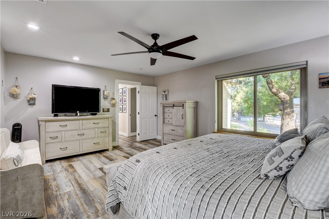 6460 Racel Street Las Vegas, NV 89131 - Photo 41 of 59 A wide window framing leafy outdoor views defines this spacious bedroom with wood-look flooring.